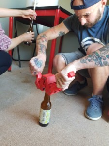 Une personne utilise un outil spécial pour fermer une bouteille de bière avec une capsule métallique