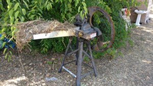 Un hache paille ancestral muni d'une manivelle pour actionner un mécanisme qui entraîne de la paille vers une lame en rotation
