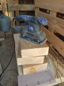 Tas de blocs de bois empilés sous une ponceuse à bande.