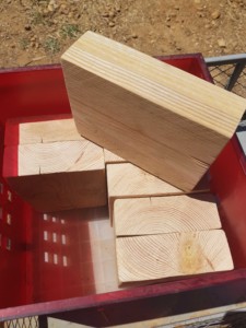 Huit blocs de bois d'environ 40 cm par 40 cm et d'une épaisseur de 10 cm dans une caisse rouge.