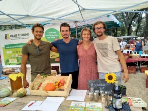 Quatre personnes se tenant côte à côté derrière le stand de l'Oasis à la fête de la tomate